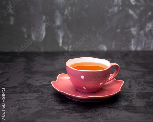 Green tea in a pink mug with white peas on a gray background