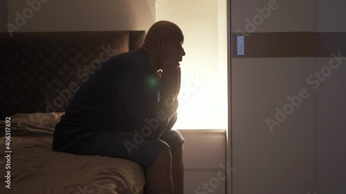 Depressed lonely old elderly black man. African American people sitting on bed in bedroom at home. Lifestyle on late night. Insomnia. Quarantine