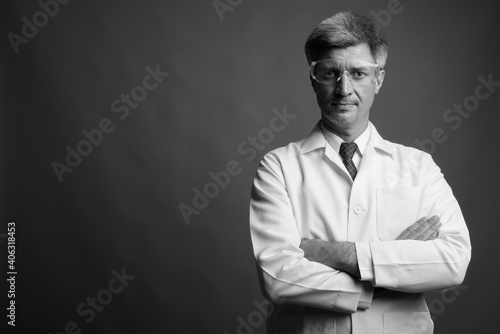 Man doctor with blond hair wearing protective eyeglasses against gray background