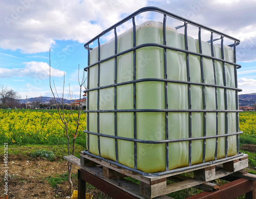 Obraz na plátne Plastic water tank in a farm field under a blue cloudy sky and sunlight