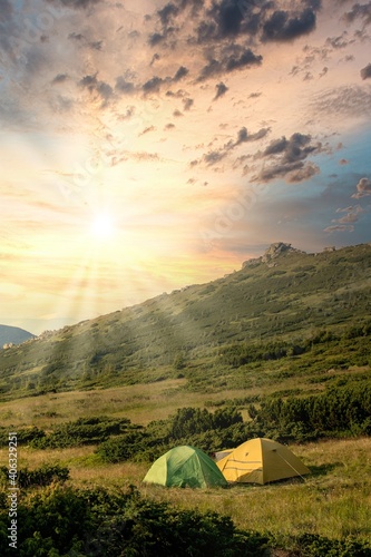 view of tourist tent in mountains at sunrise or sunset. Camping background. Adventure travel active lifestyle freedom concept. Summer vacation.