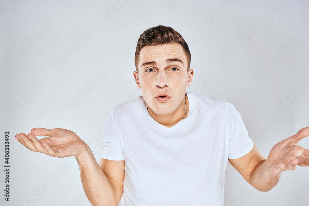 Nice man in a white t-shirt gestures with his hands emotions surprise studio Nice man in a white t-shirt gestures with his hands emotions surprise studio