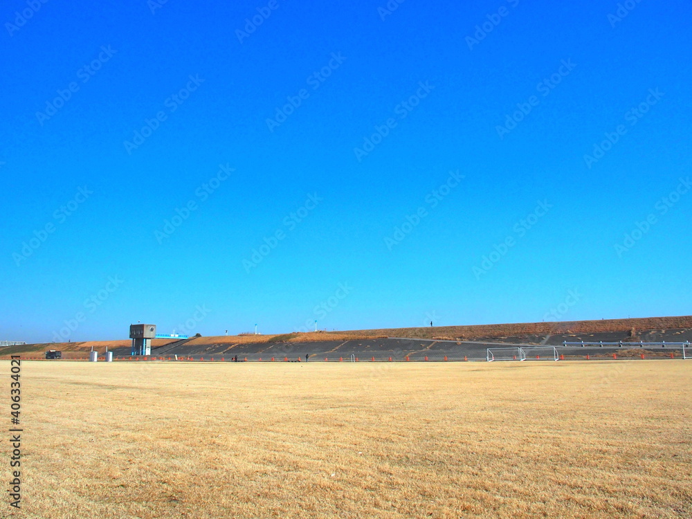 枯れ芝のサッカー場のある冬の江戸川河川敷風景