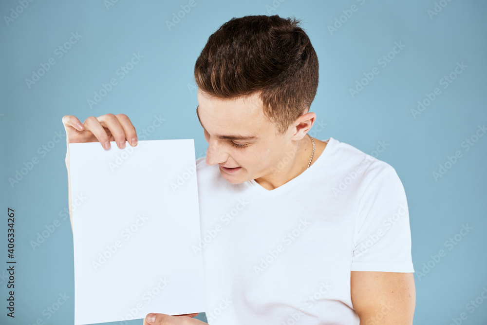 man holding a sheet of paper in his hands white t-shirt cropped view blue background man holding a sheet of paper in his hands white t-shirt cropped view blue background