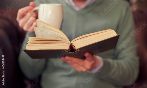 man reading a book with a mug of coffee in the morning
