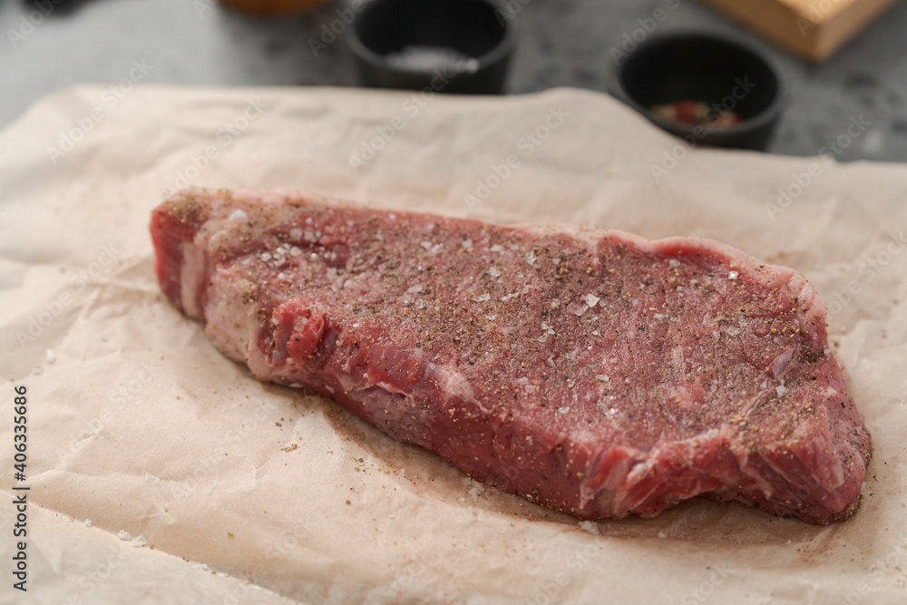 closeup raw seasoned new york steak on concrete countertop background