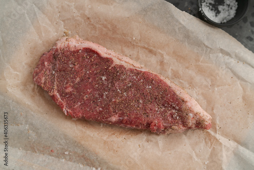 Top view of raw seasoned new york steak on concrete countertop background
