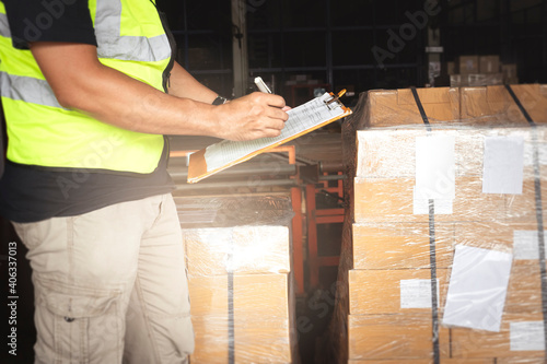 Warehouse worker holding clipboard his doing inventory management the product. Checking stock, Warehousing. Cargo shipment boxes.
