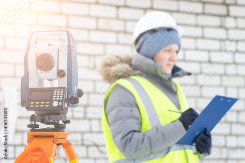 a female engineer surveyor works with an electronic total station in winter, a tool for performing geodetic, construction and cadastral works on the ground, selective focusing, tinting.
