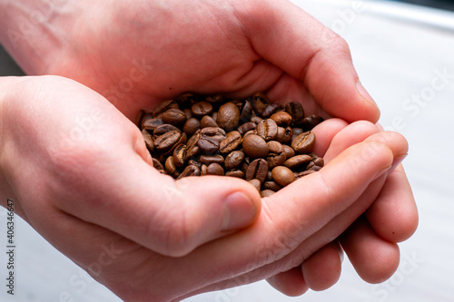 whole coffee beans in the palms of a person