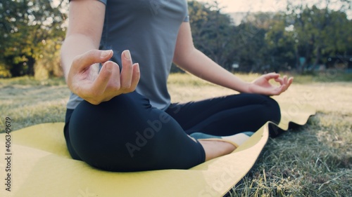 Fototapeta Naklejka Na Ścianę i Meble -  Close-up hands. Women do yoga outdoors at sunrise in lotus position exercising and meditating in the morning.