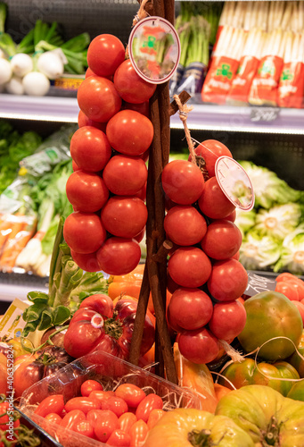 Fototapeta Naklejka Na Ścianę i Meble -  Racimos de tomates rojos colgados peculiarmente para atraer la venta.