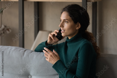 Foto Young Caucasian woman sit on sofa at home talk on cellphone use good mobile provider connection