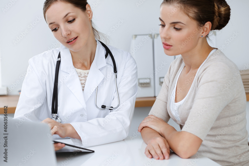 Doctor and patient are sitting and discussing health examination results in clinic office. Health care, medicine and good news concepts Doctor and patient are sitting and discussing health examination results in clinic office. Health care, medicine and good news concepts