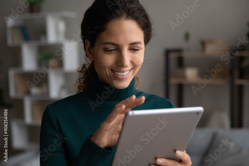Happy young woman look at tablet screen talk on video call or have webcam conference on gadget online. Smiling millennial Caucasian female use pad device browse wireless internet. Technology concept. © fizkes