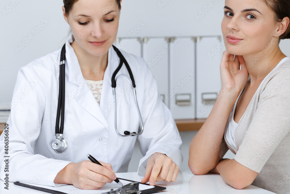 Doctor and patient are sitting and discussing health examination results in clinic office. Health care, medicine and good news concepts Doctor and patient are sitting and discussing health examination results in clinic office. Health care, medicine and good news concepts