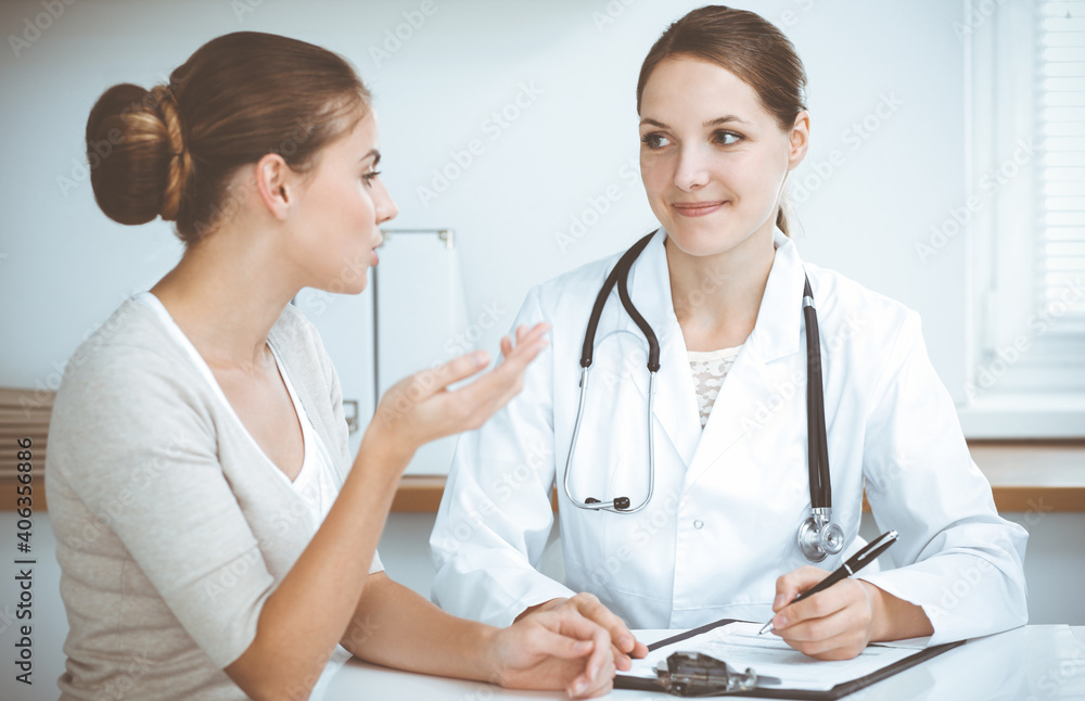Doctor and patient are sitting and discussing health examination results in clinic office. Health care, medicine and good news concepts Doctor and patient are sitting and discussing health examination results in clinic office. Health care, medicine and good news concepts