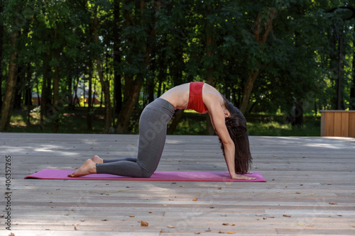 Pretty woman doing yoga exercises in the park. Exercise in the fresh air