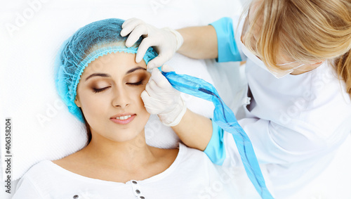 Professional beautician doing eyebrow tattoo at woman face. Permanent brow makeup in beauty salon  closeup. Cosmetology treatment