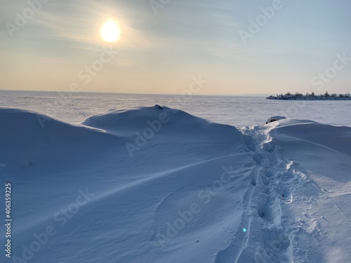 Fotografi Winter Trail on a frozen river consecrated by the sun