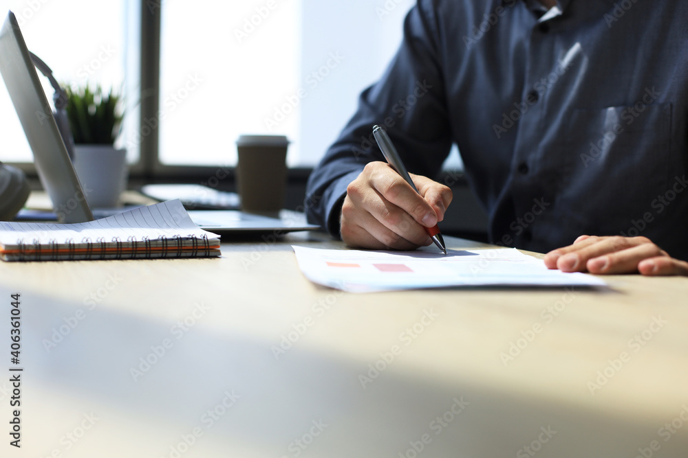 Businessman writes in a notebook while sitting at a desk. Businessman writes in a notebook while sitting at a desk.