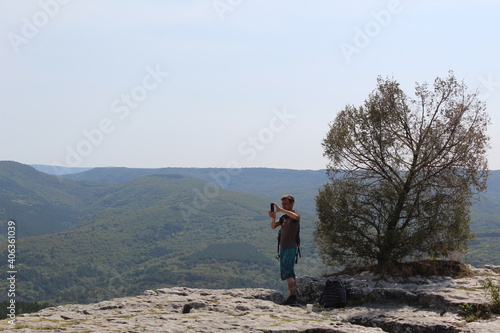 a man standing in the mountains takes a beautiful landscape in autumn on his mobile phone