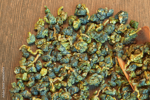 фотографія Fresh  organic Taiwan oolong tea Li shan with wooden spoon close up on light b