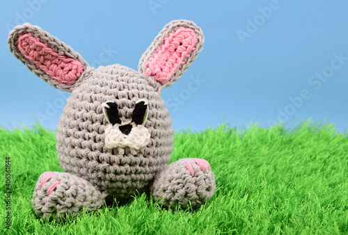 Rabbit knitted from gray yarn on green grass