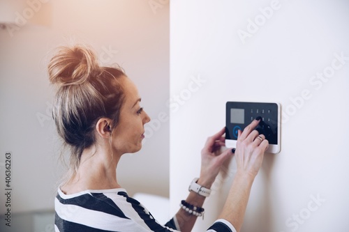 Blonde woman entering code on home security alarm keypad. Alarm code. photo