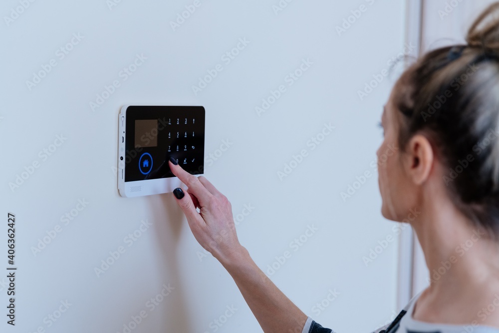 The woman turns on the alarm in her apartment. Protection and security.