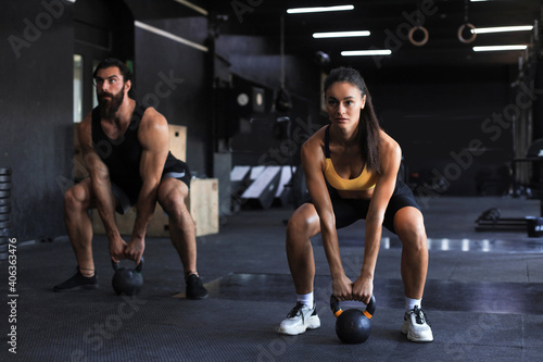 Fototapeta Naklejka Na Ścianę i Meble -  Fit and muscular couple focused on lifting a dumbbell during an exercise class in a gym.