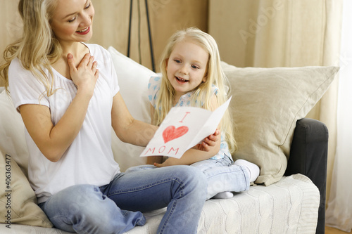 Happy mother day. Child daughter congratulates mom and gives her postcard with heart drawing. Family and childhood concepts