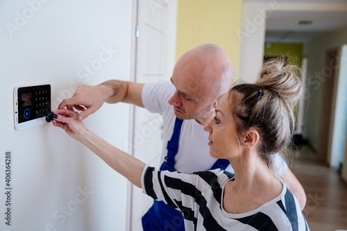 A handsome alarm fitter explains to the woman how to handle the alarm. Protection against burglars. Security at home photo