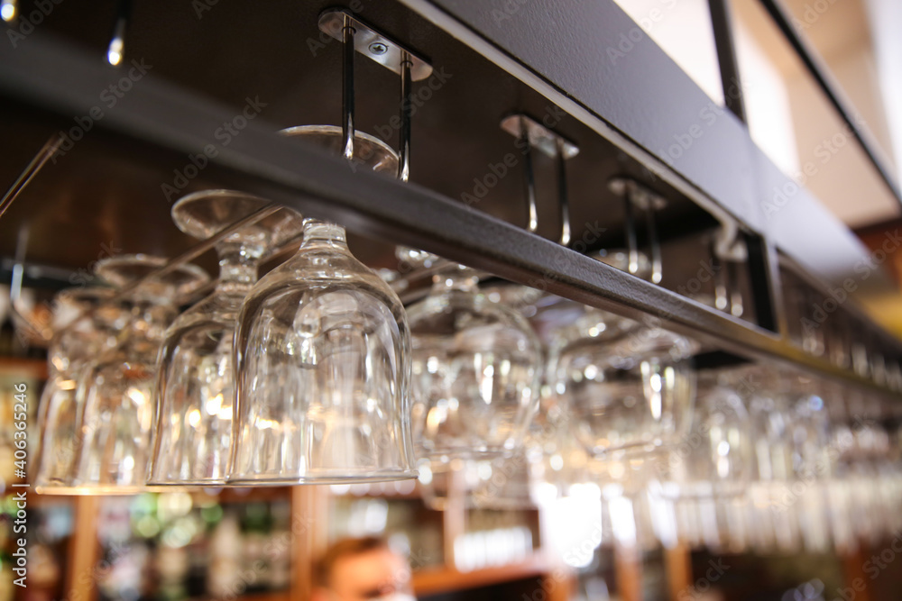 Many clean glasses on metal rack in restaurant