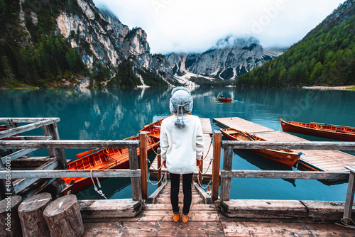 Woman standing in front of an alpine lake at Braies, Italy - Tourist hiking mountains looking the view - Travel, wanderlust and lifestyle concept.