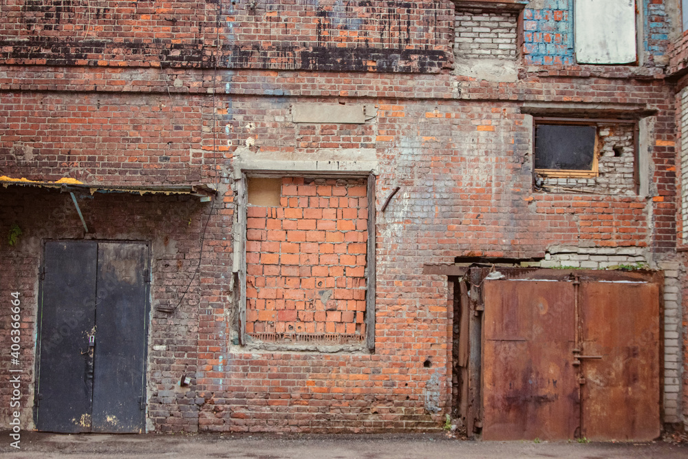 A large fragment of the brick wall of the old factory with bricked-up parts and windows