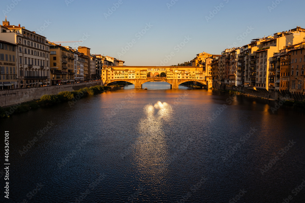 view of the famous Ponte Vecchio bridge over the Arno river and the hiding houses before sunset.