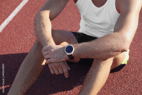 Man with fitness tracker after training at stadium, closeup