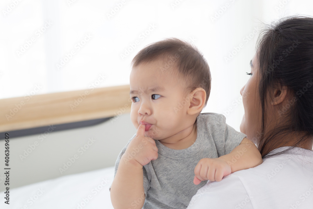 Young asian mother holding little baby girl together in the bedroom at home, mom carry child and care, woman and kid with carefree, toddler and parent, emotion and expression, family concept. Young asian mother holding little baby girl together in the bedroom at home, mom carry child and care, woman and kid with carefree, toddler and parent, emotion and expression, family concept.