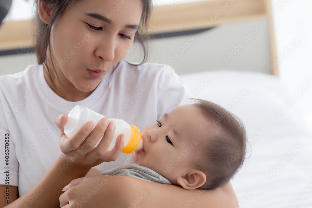 Young asian mother embracing and feeding little baby girl with bottle of milk at home, newborn innocence drinking with mom satisfied, relationship and bonding of mum and child, family concept. Young asian mother embracing and feeding little baby girl with bottle of milk at home, newborn innocence drinking with mom satisfied, relationship and bonding of mum and child, family concept.