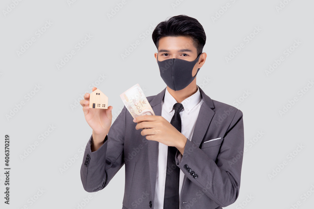 Young asian businessman in face mask holding money Thai and home isolated on white background, pandemic and crisis of economic, business man and investment property during disease covid-19. Young asian businessman in face mask holding money Thai and home isolated on white background, pandemic and crisis of economic, business man and investment property during disease covid-19.