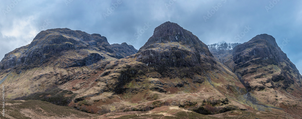 Majestic moody landscape image of Three Sisters in Glencoe in Scottish Highlands on a wet Winter day wit high water running down mountains
