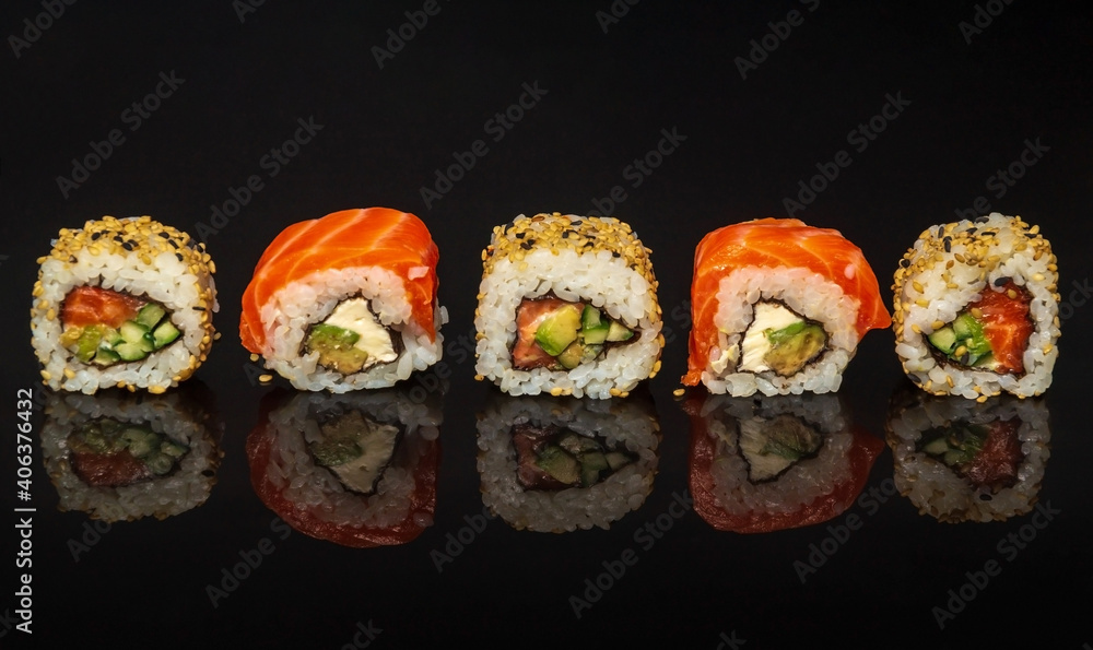 Five maki rolls in a row with salmon, avocado, tuna and cucumber isolated on black background. Fresh hosomaki pieces with rice and nori. Close up of delicious japanese food with sushi roll Five maki rolls in a row with salmon, avocado, tuna and cucumber isolated on black background. Fresh hosomaki pieces with rice and nori. Close up of delicious japanese food with sushi roll