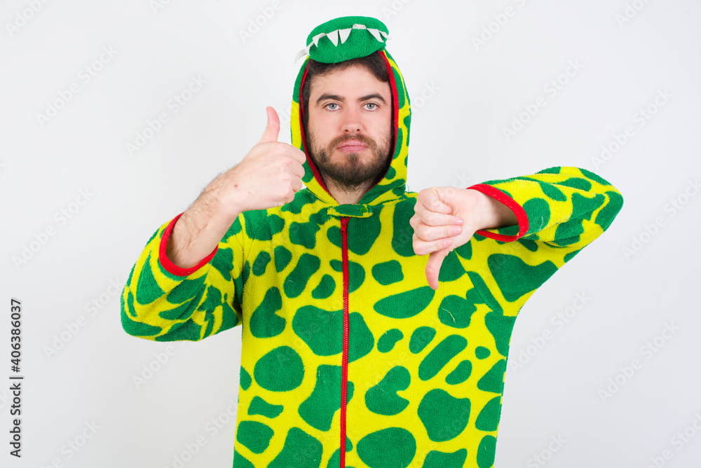 Fototapeta premium Young caucasian man wearing a pajama standing against white background showing thumbs up and thumbs down, difficult choose concept