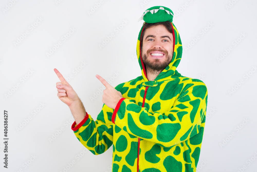 Fototapeta premium Young caucasian man wearing a pajama standing against white background indicating finger empty space showing best low prices, looking at the camera