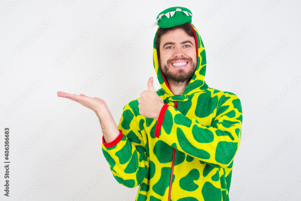 Fototapeta premium Young caucasian man wearing a pajama standing against white background Showing palm hand and doing ok gesture with thumbs up, smiling happy and cheerful.