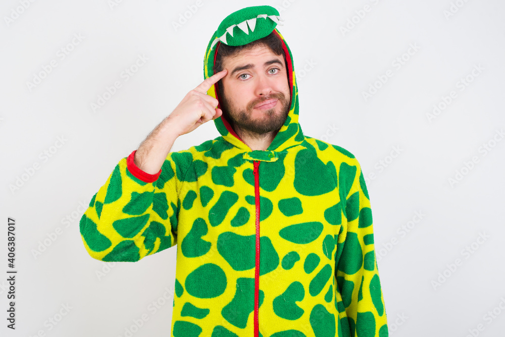 Fototapeta premium Young caucasian man wearing a pajama standing against white background tries to memorize something, keeps fore finger on temple, reminds information for exam,