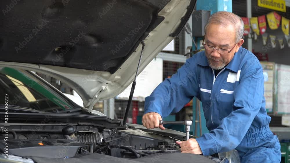 asian mechanic senior man using socket spanner wrench repairing a car in workshop at auto car repair service center. car engineer old man inspection vehicle details asian mechanic senior man using socket spanner wrench repairing a car in workshop at auto car repair service center. car engineer old man inspection vehicle details