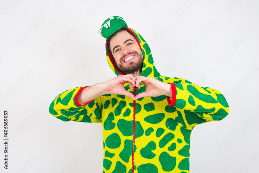 Fototapeta premium Young caucasian man wearing a pajama standing against white background smiling in love doing heart symbol shape with hands. Romantic concept.
