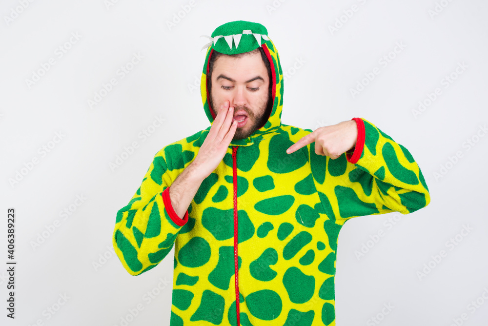 Fototapeta premium Shocked Young caucasian man wearing a pajama standing against white background look surprisedly down, indicates at blank with fore finger, Scared model